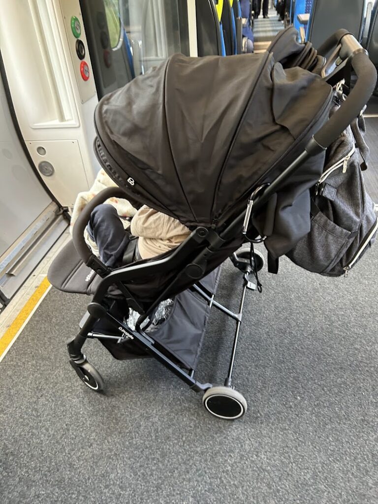 Changing bag clipped to pushchair handlebar with carabiner clip on a train