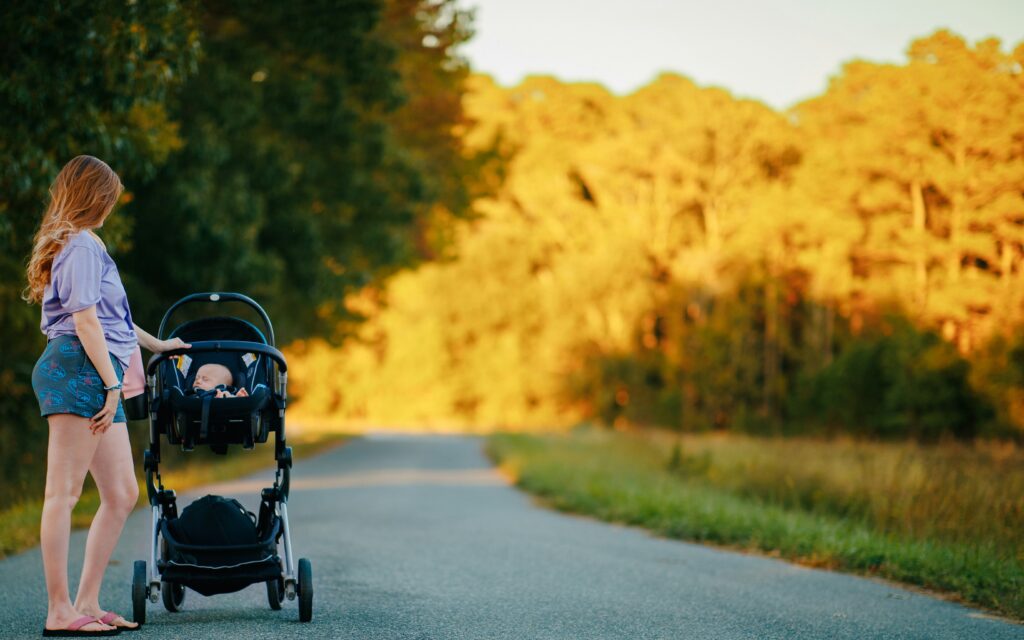 Mother pushing baby in pushchair on a sunny country path