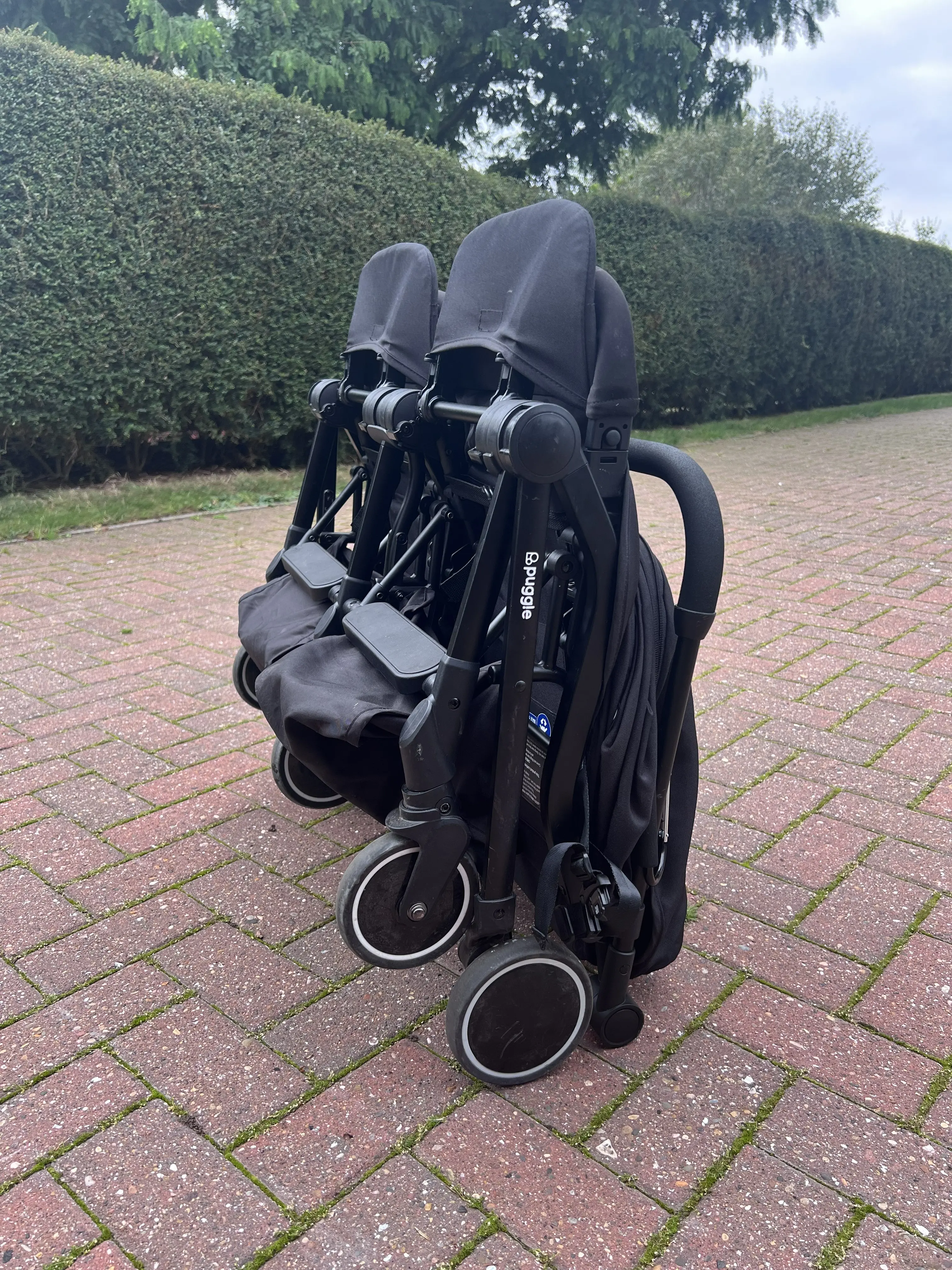 Puggle City Traveller double pushchair folded freestanding on driveway